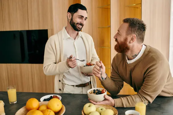 Два счастливых человека, гей-пара, которые завтракают на современной кухне, демонстрируя любовь и дружеские отношения. — стоковое фото