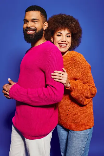 Ein junger afroamerikanischer Mann und eine junge Frau in lebhafter Freizeitkleidung umarmen sich eng und zeigen Freundschaft und Zusammengehörigkeit. — Stockfoto