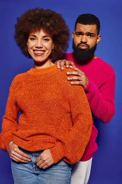 Un jeune homme et une jeune femme afro-américaine en tenue décontractée vibrante se tiennent côte à côte, rayonnant d'amitié et de diversité. — Photo de stock