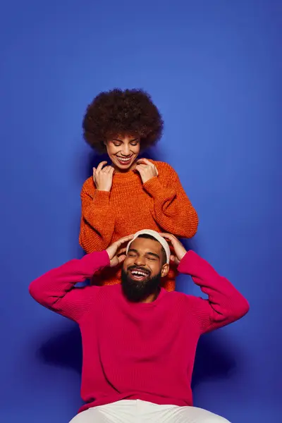 A young African American man sits on top of a womans head in vibrant casual attire, showcasing friendship. — Stock Photo