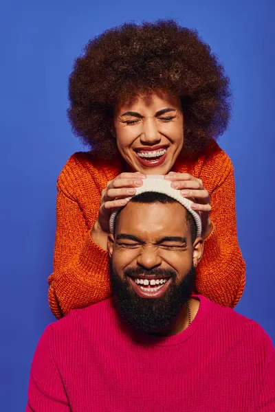 A young African American woman holding a male head, both smiling, showcasing friendship and connection. — Stock Photo