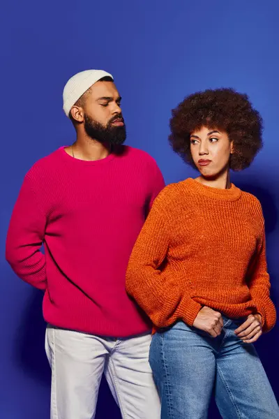 Мужчина и женщина, друзья в яркой повседневной одежде, стоят вместе в гармонии на синем фоне. — стоковое фото