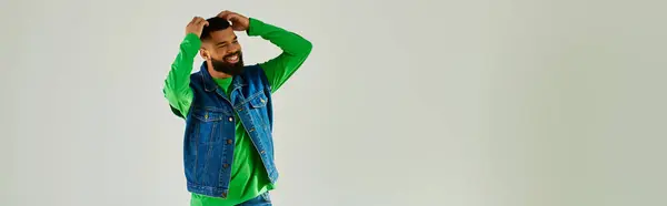A man with a beard wearing a green long sleeve and blue jeans. — Stock Photo
