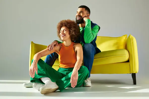 Happy African American friends in vibrant clothes sitting on a yellow couch, showcasing a strong bond and connection. — Stock Photo