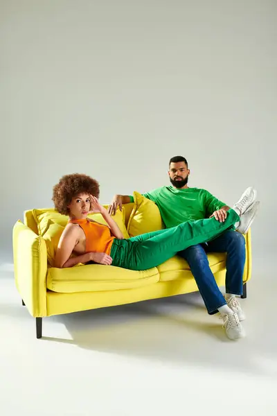 Amis afro-américains heureux assis sur le canapé jaune, mettant en valeur l'amitié et la connexion en tenue vibrante. — Photo de stock