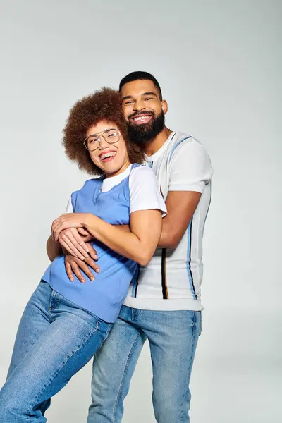Un homme et une femme afro-américains élégamment habillés posent pour une photo sur un fond gris, mettant en valeur leur amitié. — Photo de stock