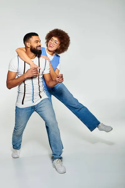An African American man in stylish clothes carries a woman on his back, showcasing friendship and trust. — Stock Photo