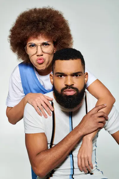 African American man with afro holding woman in stylish attire on grey background, symbolizing friendship. — Stock Photo