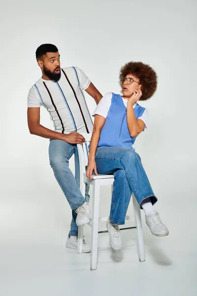 Un uomo e una donna afroamericani in abiti eleganti, seduti su sgabelli uno accanto all'altro, in mostra amicizia e cameratismo. — Foto stock