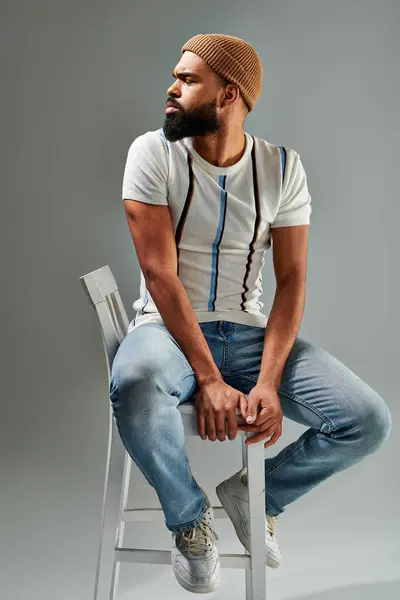 A man with a beard sits thoughtfully on a chair, deep in contemplation, exuding a sense of wisdom and introspection. — Stock Photo
