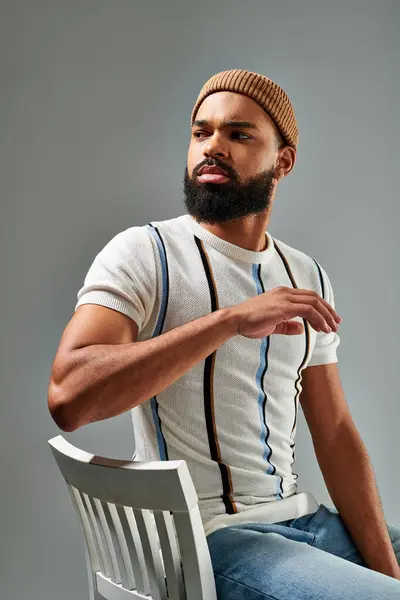 A man exudes power and elegance as he perches atop a sleek white chair, commanding attention and embodying sophistication. — Stock Photo