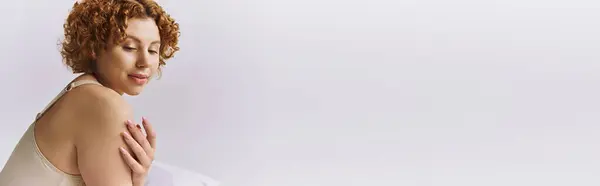 A young, curvy redhead woman with curly hair lays gracefully on a white background. — Stock Photo