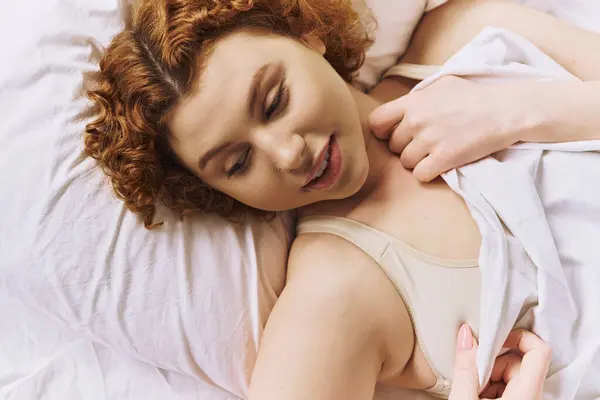 A young, curvy redhead woman in lingerie lays on a bed — Foto stock