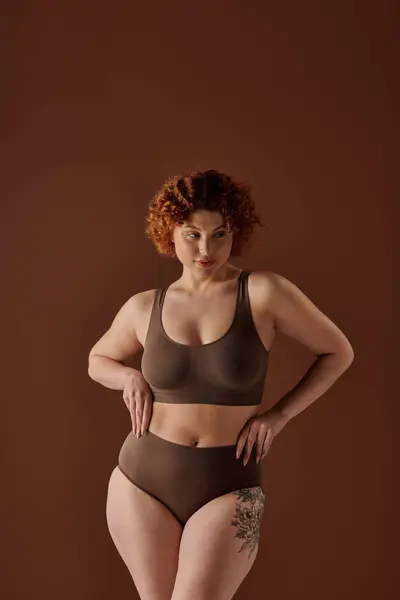 A curvy redhead woman wearing a brown bra and panties, exuding confidence and beauty. — Stockfoto