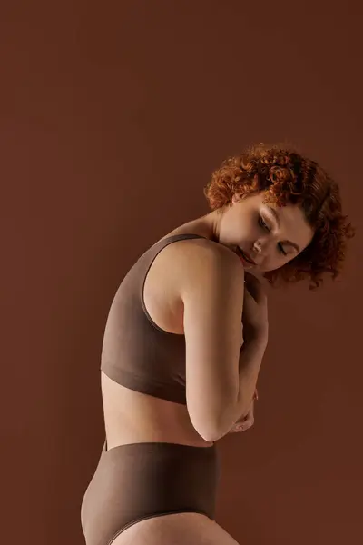 Curvy redhead woman posing confidently in a stylish brown bikini. — стокове фото
