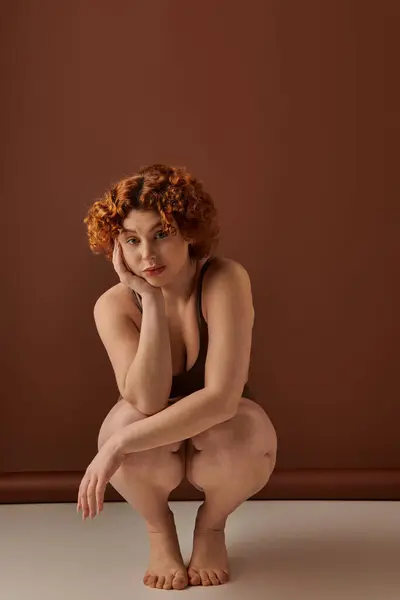 A curvy redhead woman crouching on the floor in her underwear. — Stock Photo