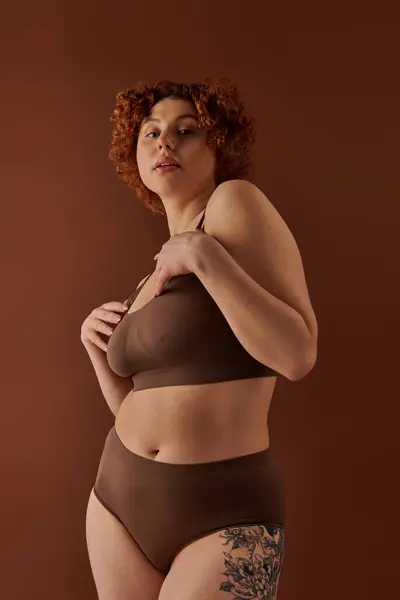 Curvy redhead woman elegantly posing in a brown bikini. — стоковое фото