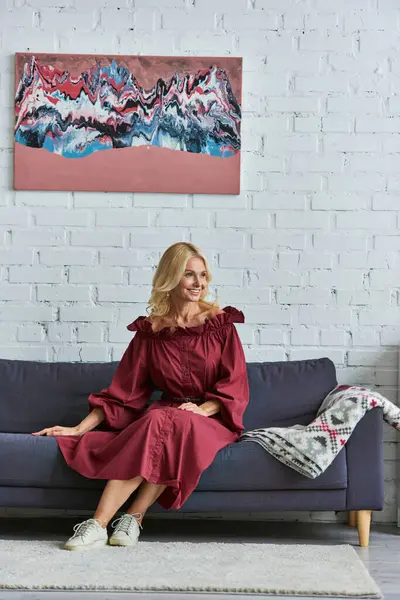 Mujer con estilo en vestido rojo sentado en un sofá. - foto de stock