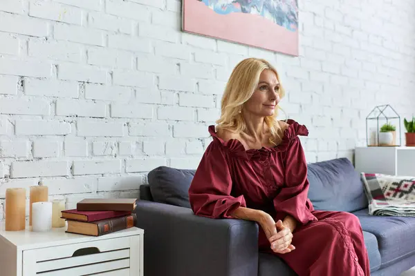 Mature woman in stylish dress on couch in chic living room. — Stock Photo