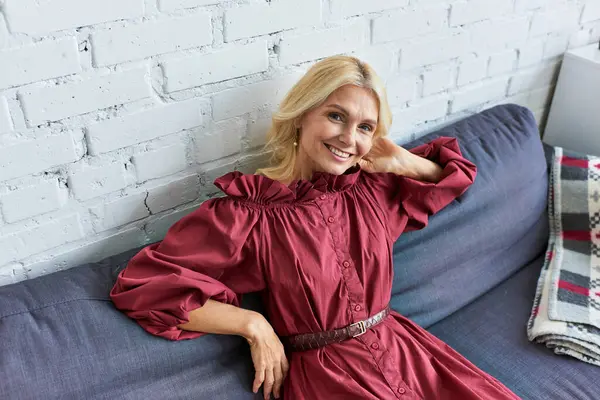 Стильная женщина в красном платье на синем диване. — Stock Photo