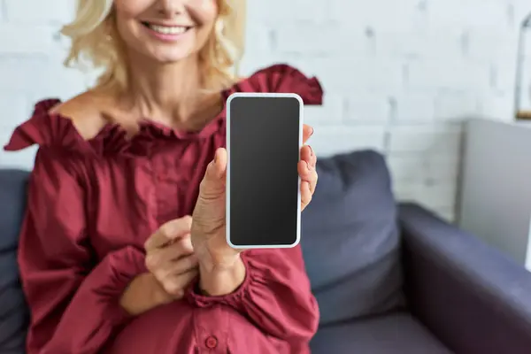 Mature woman in red shirt holds a cell phone. — Stock Photo