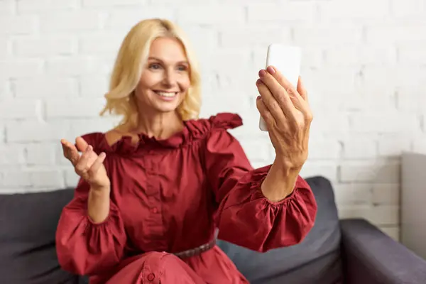 Mulher elegante em traje chique, sentado no sofá, navegando telefone celular. — Fotografia de Stock