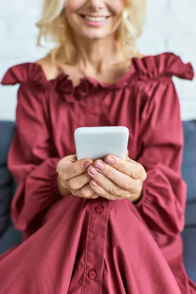 Femme élégante en robe rouge absorbée dans la tablette, profitant d'un moment calme à la maison. — Photo de stock