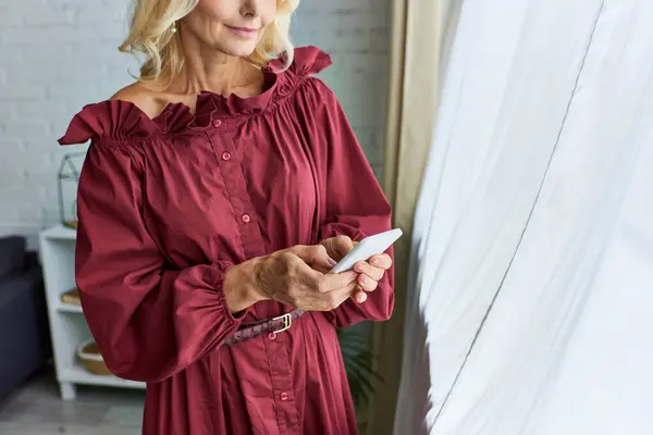 Stylish woman in red dress captivated by her phone. — Stock Photo
