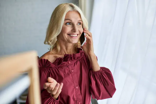 Mature woman in a red shirt having a phone conversation. — Stock Photo