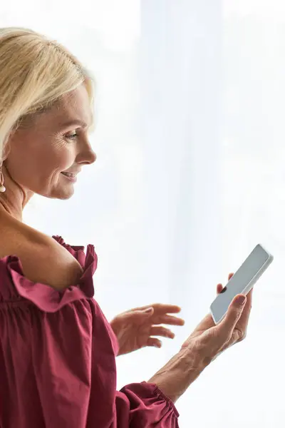 Stylish woman in a red dress engrossed in phone. — Stock Photo