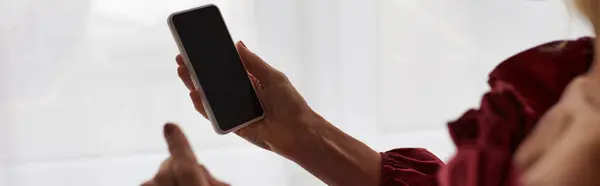 A mature woman in a striking red dress, holding a cellphone. — Stock Photo