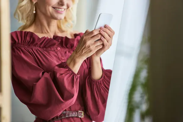 Stylish woman in red top captivated by her cell phone. — Stock Photo