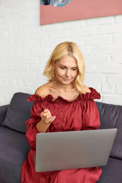 Una donna sofisticata in abiti eleganti, avvolta nel suo computer portatile sul divano. — Foto stock