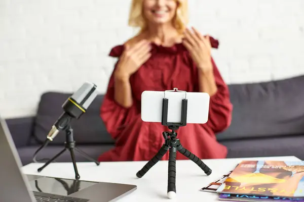 Mature woman in red dress records podcast on beauty from laptop. — Stock Photo