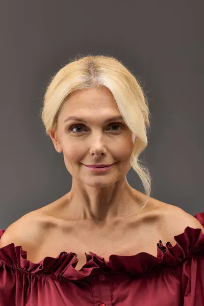 Mature woman with blonde hair, dressed in a striking red outfit. — Stock Photo