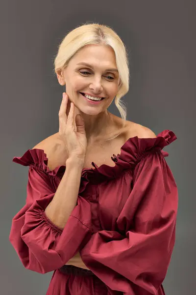 Uma mulher elegante madura em um vestido chique vermelho atinge uma pose. — Fotografia de Stock