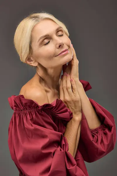Elegant lady in a red top, deep in thought, hand resting on face. — Stock Photo