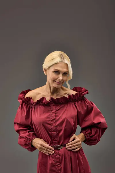 A mature, elegant woman in a chic red dress striking a pose. — Stock Photo