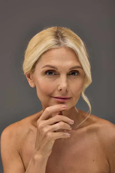 A mature woman confidently poses against a gray backdrop. — Stock Photo