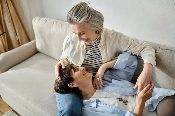A loving mature lesbian couple relaxing and chatting together on a cozy couch. — Stock Photo
