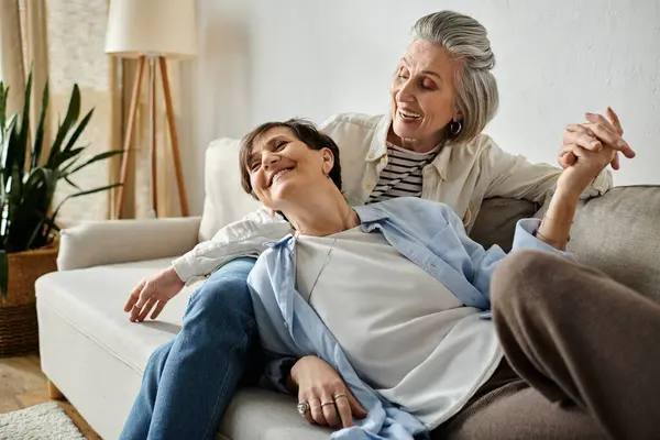 Due donne anziane sedute da vicino su un divano, che condividono un momento di compagnia e amore. — Foto stock