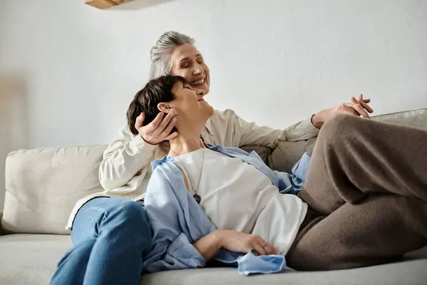 A loving mature lesbian couple sitting closely together on a couch. — Stock Photo