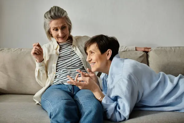 Two elderly women sit on a comfy couch, engrossed in a deep conversation. — Stock Photo