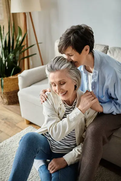 Un momento commovente mentre due donne anziane si abbracciano sul divano. — Foto stock