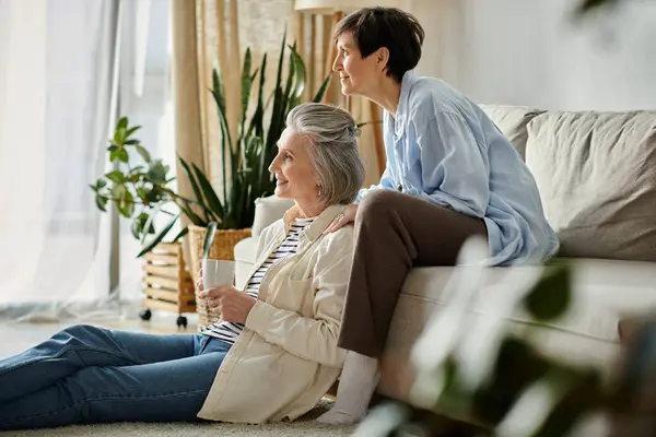 Две пожилые женщины мирно сидят на уютном диване в гостиной. — стоковое фото