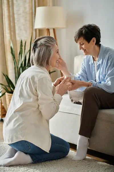 Mature lesbian couple engaged in heartfelt conversation on a cozy couch. — Stock Photo