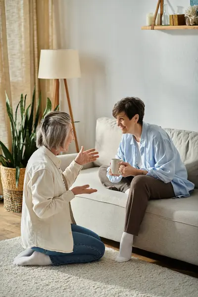 Ein liebevolles reifes lesbisches Paar, das sich auf einer gemütlichen Wohnzimmercouch in ein tiefes Gespräch vertieft. — Stockfoto