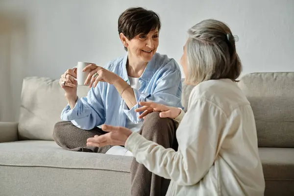 A loving mature lesbian couple engage in deep conversation while seated on a cozy couch. — Stock Photo