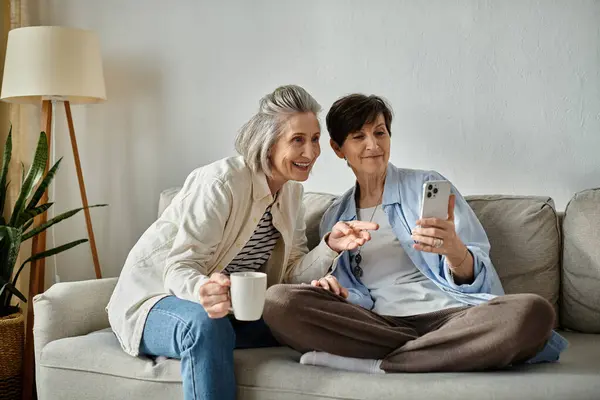 Two elderly women on a sofa mesmerized by their phones. — Stock Photo