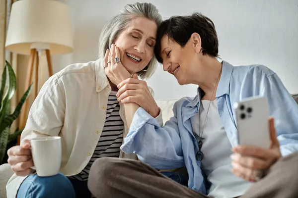 Two elderly women sitting on a couch and engrossed in their phones. — Stock Photo